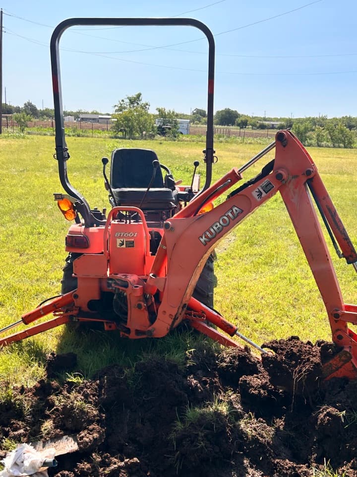 Compact excavator at an active underground plumbing repair site